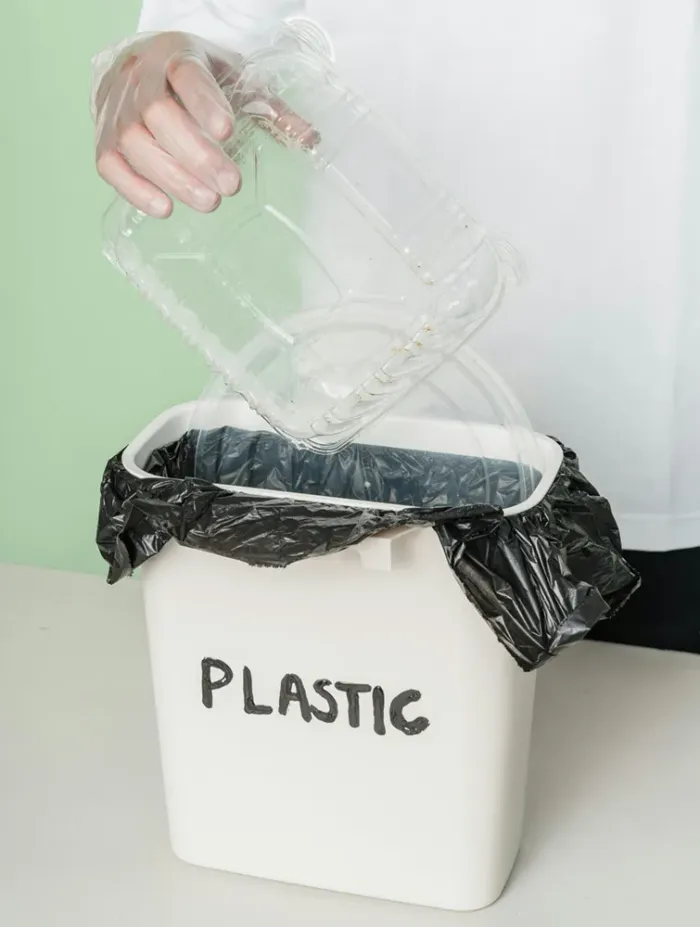 Envase de plástico limpio depositado en un contenedor de reciclaje correctamente etiquetado
